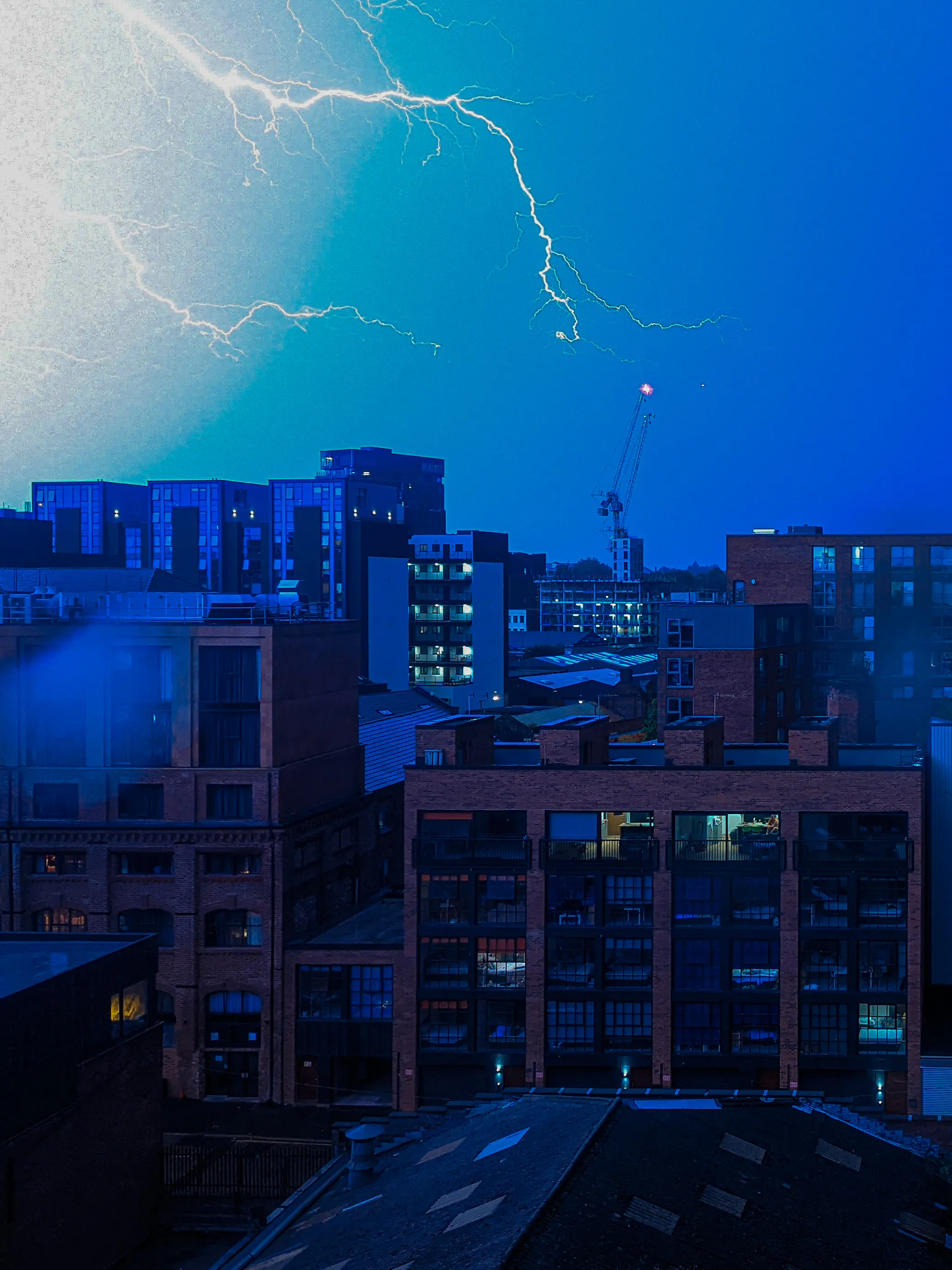 Lightning striking over a dense city skyline at night, blue colour grade